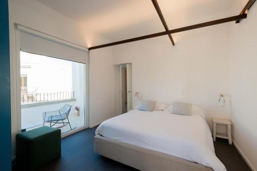 a bedroom with a white bed and a large window at Arya Nobile Dimora in Carovigno