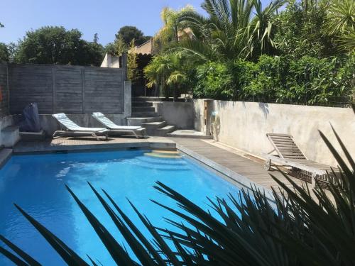 - une piscine avec 2 chaises longues à côté d'un mur dans l'établissement 2 pièces rez-de-jardin dans maison avec piscine, à Villeneuve-Loubet