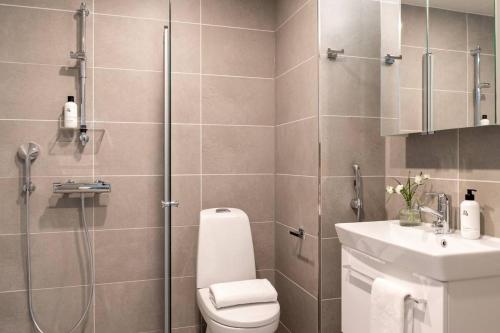 a bathroom with a shower and a toilet and a sink at Cozy apartment right next to metro station in Espoo