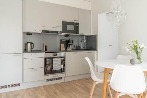 a kitchen with white cabinets and a table and chairs at Cozy apartment right next to metro station in Espoo