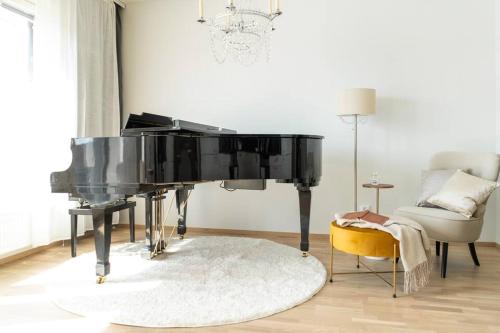 a black piano in a living room with a chair at Cozy apartment right next to metro station in Espoo
