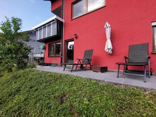 two chairs and an umbrella next to a red building at Ferienwohnung Sabine in Hornberg
