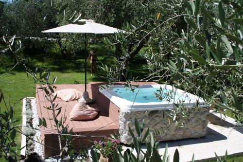 a hot tub in a garden with an umbrella at Casaliva Relais in Bardolino