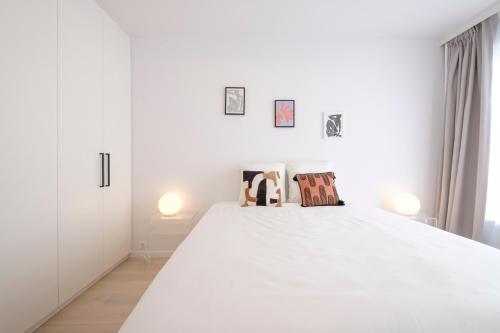 a white bedroom with a large white bed with two pillows at Trendy 1 bedroom flat near Schuman and Berlaymont in Brussels