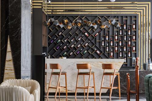 a bar with chairs and a wall of wine bottles at Panarams Tashkent Hotel, a member of Radisson Individuals in Tashkent