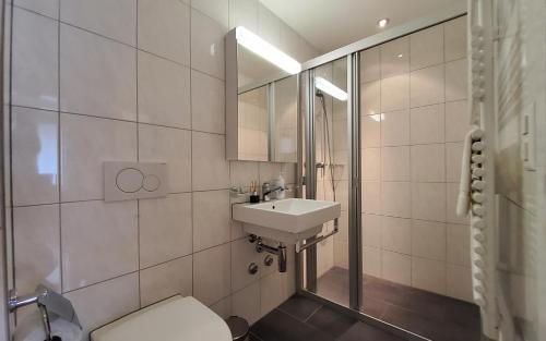a bathroom with a sink and a toilet and a mirror at Apartment Via Surpunt - Bella - 3 Rooms in St. Moritz
