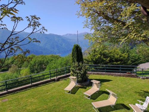 a group of chairs sitting on a lawn with mountains in the background at Chalet Merlo by Interhome in Porlezza