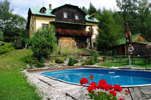 a house with a swimming pool in front of a house at Penzion u Lebedů in Kašperské Hory