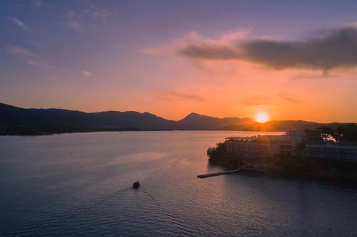 a boat in the water with the sunset in the background at Xenia Poros Image Hotel in Poros