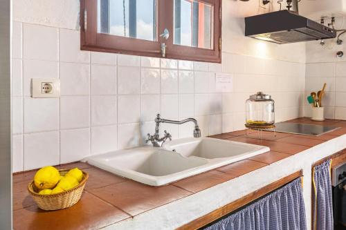 a kitchen counter with a sink and a basket ofmons at Casa Rural La Caldera in Teror