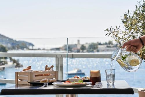 a person pouring a glass of wine on a table at Xenia Poros Image Hotel in Poros