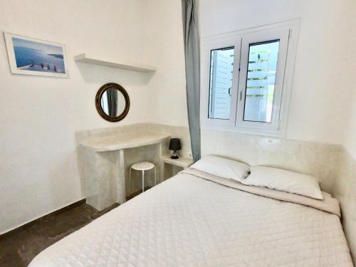 a white bedroom with a bed and a window at Anny Studios Perissa Beach in Perissa