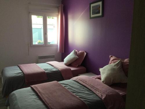 2 bedden in een kamer met paarse muren en een raam bij La Petite Allée in Wimereux