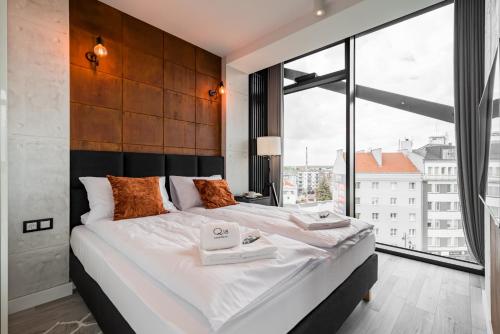 a bedroom with a large bed and a large window at Q18 ApartHotel in Bydgoszcz