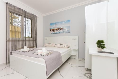 a white bedroom with a bed and a window at Villa Božica - sea view stone villa with free parking in Makarska