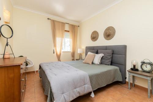 um quarto com uma cama e um relógio na parede em Cabanas Green Apartment & Loft. em Cabanas de Tavira