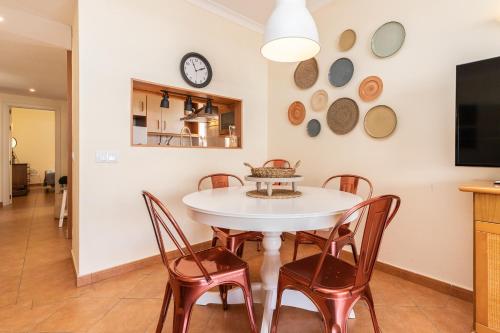 a kitchen and dining room with a white table and chairs at Cabanas Green Apartment & Loft. in Cabanas de Tavira