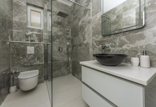 a bathroom with a sink and a glass shower at Villa Božica - sea view stone villa with free parking in Makarska