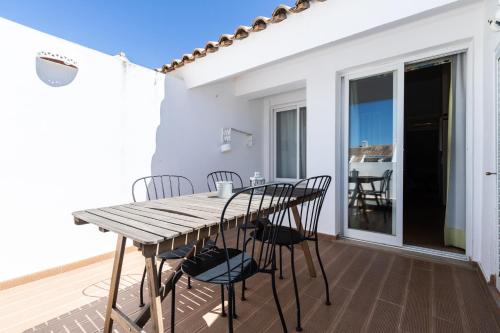 a wooden table and chairs on the balcony of a house at Cabanas Green Apartment & Loft. in Cabanas de Tavira