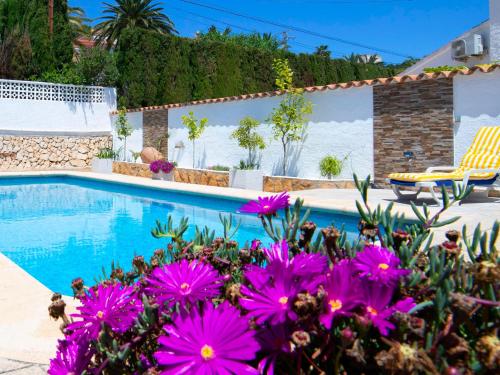 a pool with purple flowers in front of a house at Holiday Home La Grippiere by Interhome in Calpe