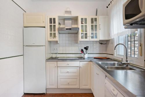 a white kitchen with a sink and a refrigerator at Poniente in Roche