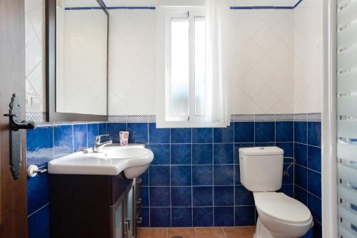 a blue tiled bathroom with a toilet and a sink at Poniente in Roche