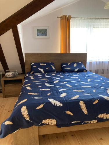 uma cama com um edredão azul e almofadas em Magnolia em Kruklanki