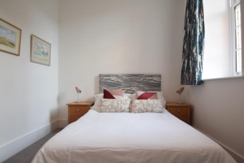 a bedroom with a white bed and two windows at Beautiful flat in luxury Graylingwell development in Chichester
