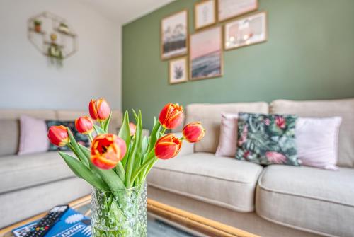 een vaas met rode tulpen op een tafel in de woonkamer bij Close to A46 City Centre Sleeps 6, 5 Beds Ensuite FREE Wi-Fi Queens House Inspire Homes in Parkside
