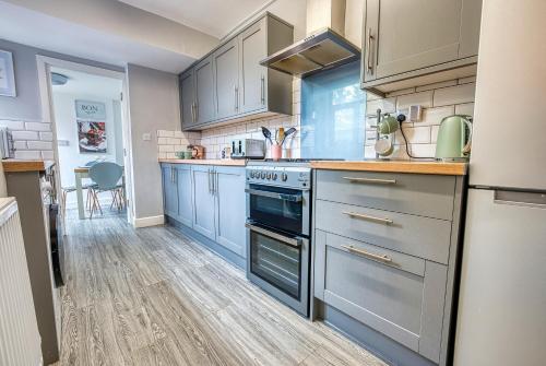 a kitchen with gray cabinets and a stove top oven at Close to A46 City Centre Sleeps 6, 5 Beds Ensuite FREE Wi-Fi Queens House Inspire Homes in Parkside