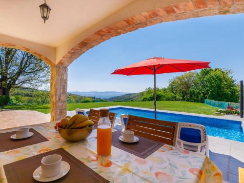 a dining table with a red umbrella and a pool at Holiday Home Panorama 1 by Interhome in Labin