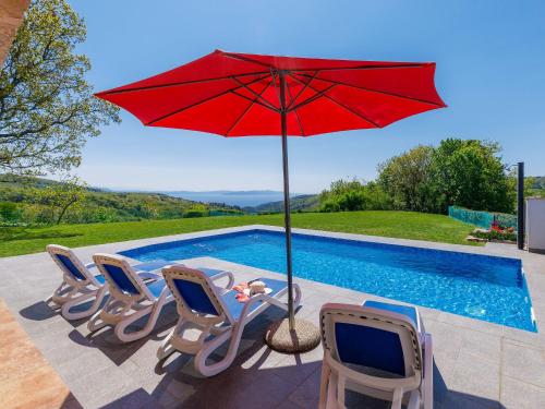 a red umbrella and chairs next to a swimming pool at Holiday Home Panorama 1 by Interhome in Labin