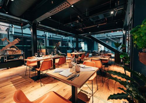 un restaurant avec des tables en bois et des chaises orange dans l'établissement Hotel Mestari, à Helsinki