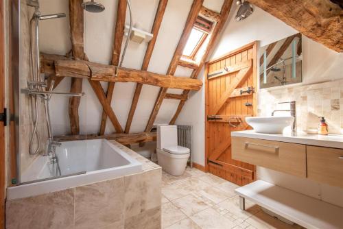 a bathroom with a tub and a toilet and a sink at Elegant peaceful barn in rural village setting close to Stratford upon Avon in Stratford-upon-Avon