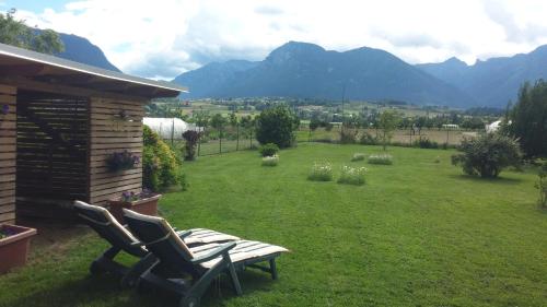 a yard with two chairs and a bench in the grass at Casa Vacanze Hartriegel in Comano Terme