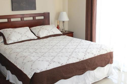 a bedroom with a bed with a white comforter and a window at Hostal Del Centro Talca in Talca