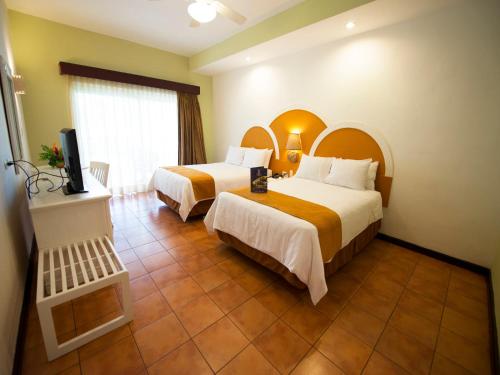 a hotel room with two beds and a television at Hotel Soleil Pacifico in Chulamar