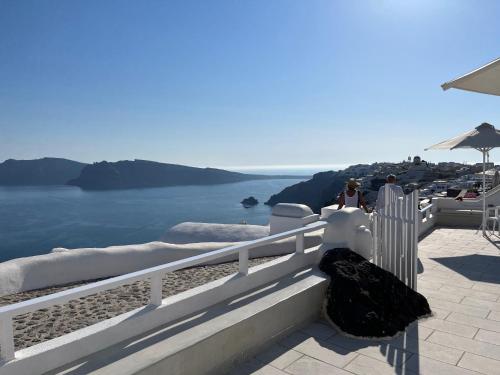 a person standing on a balcony looking at the ocean at Olympic Villas in Oia