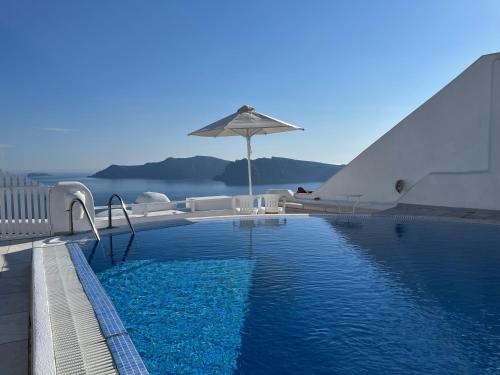 a swimming pool with an umbrella and chairs and a table at Olympic Villas in Oia