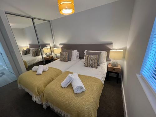 een slaapkamer met 2 bedden en handdoeken bij 2 Putsborough - Luxury Apartment at Byron Woolacombe, only 4 minute walk to Woolacombe Beach! in Woolacombe