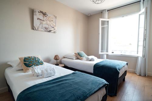 2 camas en una habitación con ventana en VILLA EYRAC - Contemporain et familial au port d'Arcachon, en Arcachon