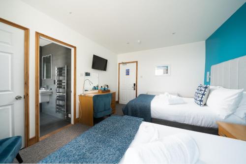 a hotel room with two beds and a bathroom at The Land's End Hotel in Sennen