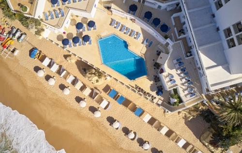 
a beach filled with lots of lawn chairs and umbrellas at Holiday Inn Algarve - Armação de Pêra, an IHG Hotel in Armação de Pêra
