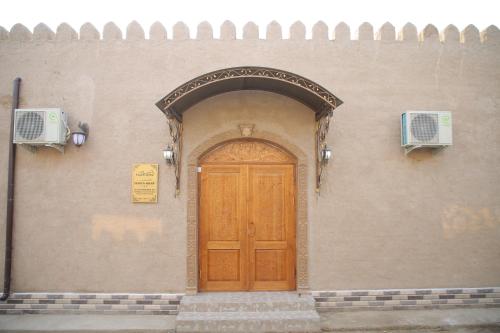 un bâtiment avec une porte en bois et une porte voûtée dans l'établissement Khiva Khan Hotel, à Khiva