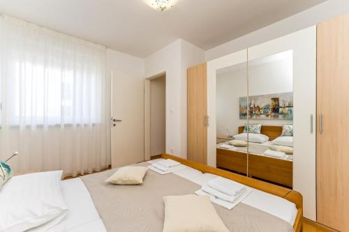 a bedroom with a large bed and a mirror at Summer Breeze Pool Apartments in Novalja