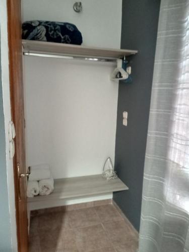 a bathroom with a shower stall with a shelf at Avra Rooms in Ermoupoli