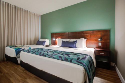 a bedroom with two beds and a green wall at Cyan Resort by Atlantica in Itupeva