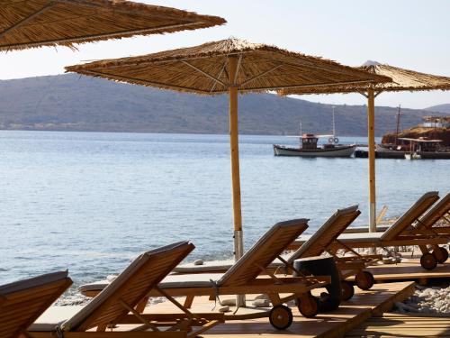 a row of chairs and umbrellas on a beach at Cayo Exclusive Resort & Spa in Elounda