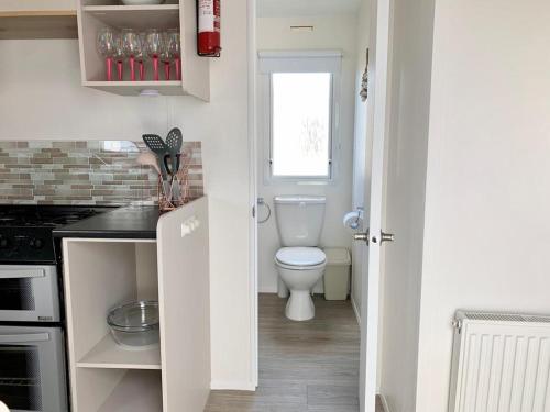 a white bathroom with a toilet and a sink at Kens caravan in Abergele