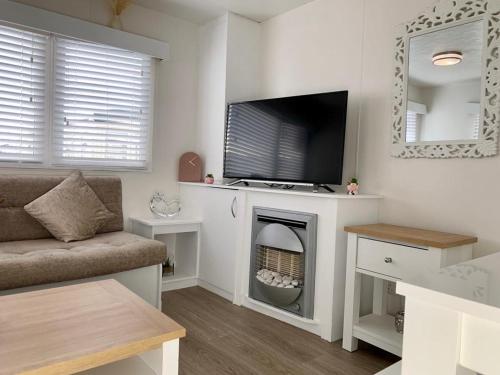 a living room with a fireplace with a tv on it at Kens caravan in Abergele